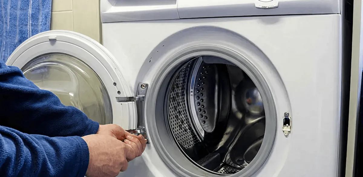 Washing machine repair handyman checking a front-load washer door and latch in Manchester, NH