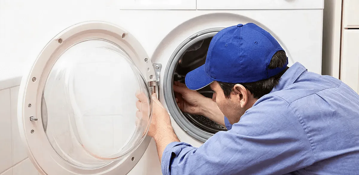 Washing machine repair handyman inspecting a front-load washer drum in Manchester, NH